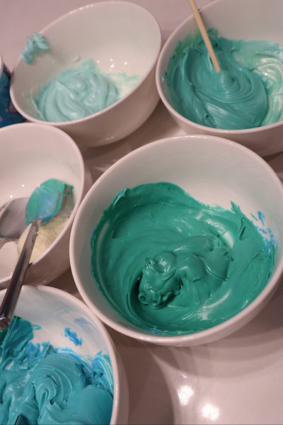 A few bowls of frosting in different shades of teal.