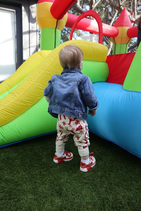 A small child looking up at a brightly colored bouncy house.