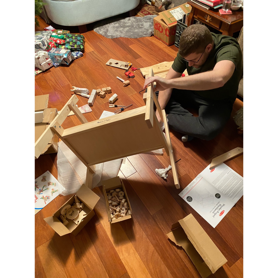 Michael putting together furniture in front of the Christmas tree.